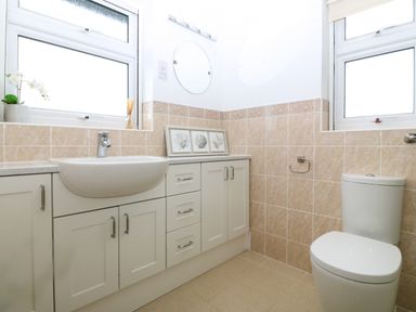 A bathroom with a toilet a sink cabinets and framed pictures on the counter at Gwylanod in Llwyngwril near Fairbourne