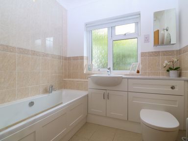 A bathroom with a bathtub sink toilet window and cabinet at Gwylanod in Llwyngwril near Fairbourne