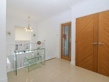 A hallway with tiled floor glass tables wooden doors and a staircase at Gwylanod Llwyngwril near Fairbourne