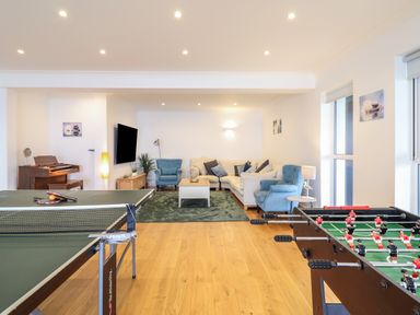 A living room with a ping pong table, foosball table, organ, sofa, chairs, and television at Gwylanod in Llwyngwril near Fairbourne