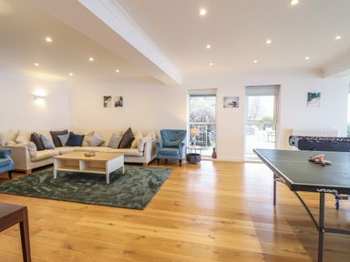 A living room with sofas and armchairs next to a coffee table and a ping pong table at Gwylanod Llwyngwril near Fairbourne