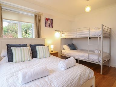 A bedroom with a double bed and bunk beds next to a window at Gwylanod in Llwyngwril near Fairbourne