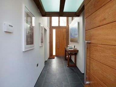 A hallway with wooden door a side table with books and towels and framed pictures on the walls at Gull Rock 4 in Rock