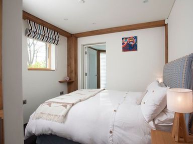 A bedroom with a bed a bedside table and lamp a window and a door at Gull Rock 4 in Rock
