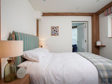 A bedroom with a bed pillows lamps a clock and a door leading to another room at Gull Rock 4 in Rock