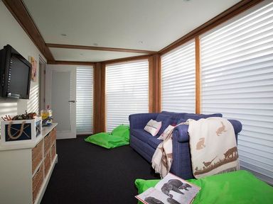 A room with a blue sofa a TV on the wall green bean bags and a white storage unit at Gull Rock 4 in Rock