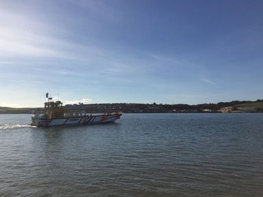 A ferry boat on the water with a town and hills in the background at Gull Rock 4 in Rock