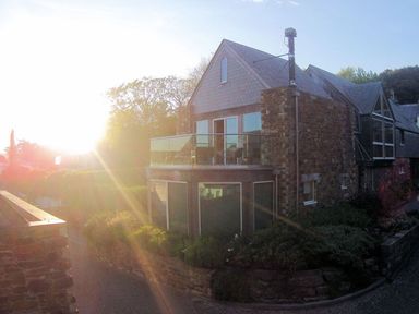 A stone house with large windows and a glass balcony surrounded by foliage at Gull Rock 4 in Rock