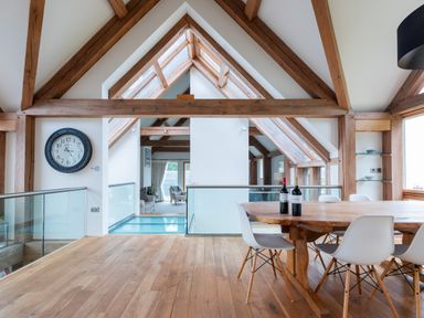 An open dining area with a wooden table and white chairs under a ceiling with wooden beams at Gull Rock 4 in Rock