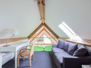 An attic room with a white desk and a chair opposite a purple sofa with a skylight window at Gull Rock 4 in Rock