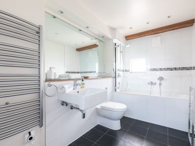 A bathroom with a wall-mounted sink toilet bathtub and towel radiator at Gull Rock 4 in Rock