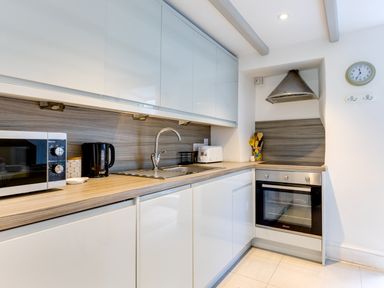 A kitchen with a microwave kettle toaster oven sink and utensils at Stokes Cottage in St Minver