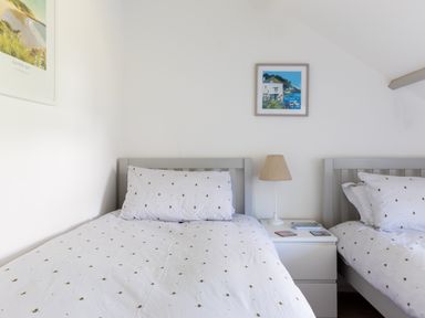 A bedroom with two single beds and a nightstand with a lamp between them at Stokes Cottage in St Minver