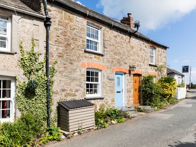 Stone cottages with blue and wooden doors and plants along the roadside at Stokes Cottage in St Minver