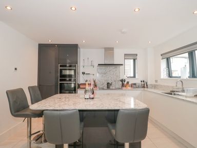 A kitchen with marble countertops and an island with chairs at Agua de Plata 16 Wakeling Island Silverlake in Dorchester