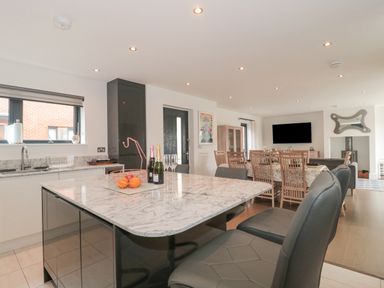 A kitchen with an island and bar stools next to a dining area with a table and chairs and a living room with a television and stove at Agua de Plata 16 Wakeling Island Silverlake Dorchester