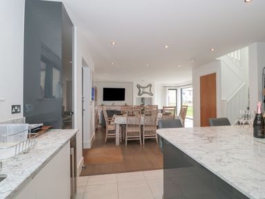 An open plan kitchen and dining area with marble countertops wooden dining table with chairs and a TV on the wall at Agua de Plata 16 Wakeling Island Silverlake in Dorchester