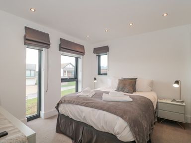 A bedroom with a bed pillows bedside table lamps and three windows at Agua de Plata 16 Wakeling Island Silverlake in Dorchester