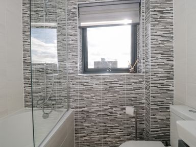 A bathroom with a bathtub shower combination a window above the toilet and tiled walls at Agua de Plata 16 Wakeling Island Silverlake in Dorchester