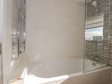 A bathroom with a bathtub shower combination and a chrome towel radiator at Agua de Plata 16 Wakeling Island Silverlake in Dorchester