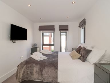 A bedroom with a bed pillows bedside tables and a wall-mounted television at Agua de Plata 16 Wakeling Island Silverlake in Dorchester
