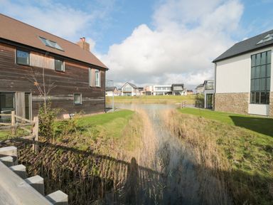 A water channel between modern houses with grassy banks at Agua de Plata 16 Wakeling Island Silverlake Dorchester