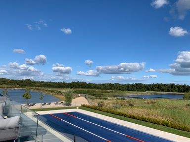 An outdoor swimming pool with a glass fence overlooking a pond and trees at Agua de Plata 16 Wakeling Island Silverlake in Dorchester