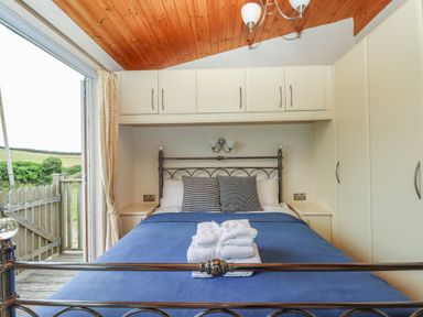 A bedroom with a metal bed frame blue bedding folded towels and cabinets above the bed at Tamar View Lodge in Millbrook