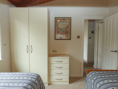 A bedroom with a wardrobe and chest of drawers between two beds at Tamar View Lodge in Millbrook
