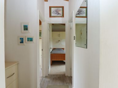 A hallway leading to a bedroom with a wooden bed and wall cabinets at Tamar View Lodge in Millbrook