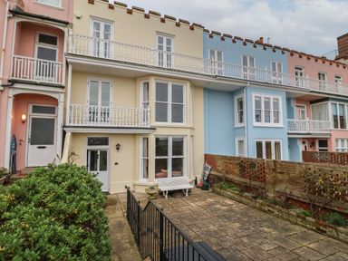 A row of three story houses with balconies and a patio area in front at 42 Crag Path in Aldeburgh