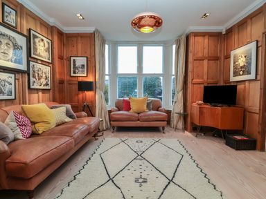 A living room with two brown leather sofas and a large window at 42 Crag Path in Aldeburgh