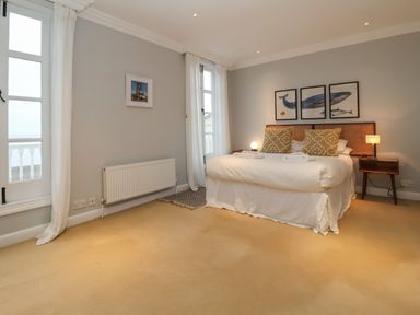 A bedroom with a large bed two nightstands and three framed whale pictures above the bed at 42 Crag Path in Aldeburgh