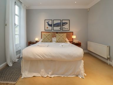 A bedroom with a double bed two pillows two lamps and three framed pictures above the bed at 42 Crag Path in Aldeburgh