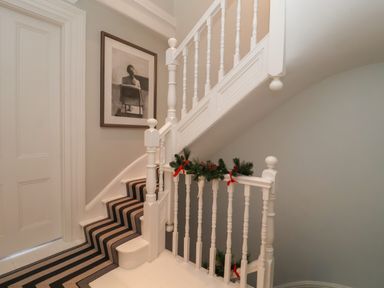 A staircase with striped carpet and framed artwork on the wall at 42 Crag Path in Aldeburgh