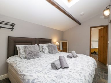 A bedroom with a double bed and rolled towels on a patterned duvet at The Old Bakehouse in Pembridge