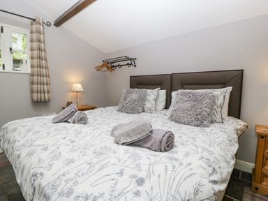 A bedroom with a double bed pillows towels bedside tables lamps and a window with curtains at The Old Bakehouse in Pembridge