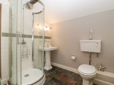 A bathroom with a corner shower enclosure a pedestal sink and a toilet at The Old Bakehouse in Pembridge