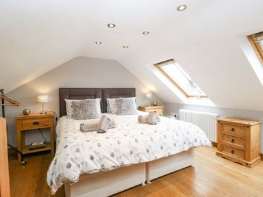A bedroom with a double bed two bedside tables with lamps wooden floor and skylight windows at The Old Bakehouse in Pembridge
