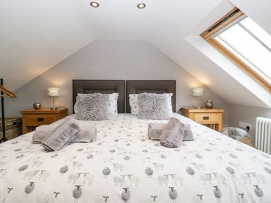 A bedroom with a bed with sheep patterned bedding two bedside tables with lamps and a skylight window at The Old Bakehouse in Pembridge