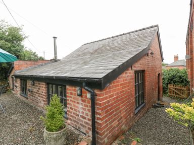 An exterior view of a single story brick building with a pitched slate roof and gravel ground at The Old Bakehouse in Pembridge