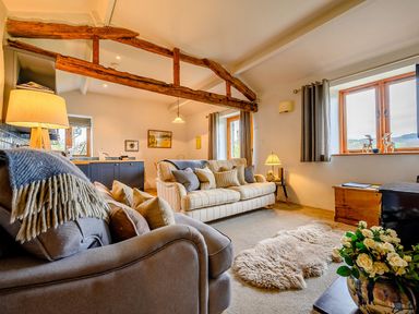A living room with sofas a lamp a sheepskin rug a wooden trunk and flowers at Shepherds Cottage in Hawkshead