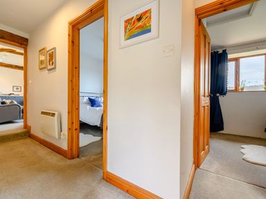 A hallway with open doors leading to a bedroom and another room with windows at Shepherds Cottage in Hawkshead