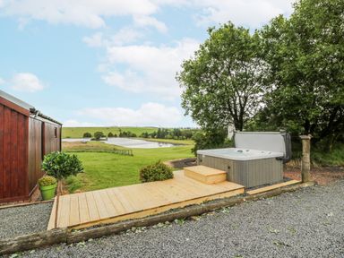 An outdoor area with a hot tub and decking at Mallard Lodge in Moscow near Galston