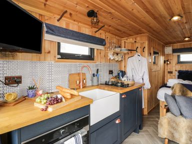 A compact kitchen with wooden countertops blue cabinets tiled backsplash and a small living space at Greenacres Carriage in Maybole