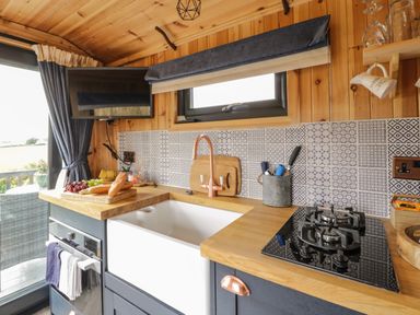 A kitchen with a farmhouse sink stove and cutting board at Greenacres Carriage in Maybole