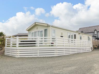 A single story mobile home with white railings and a gravel driveway at Gwel Eryri in Penmynydd near Llanfairpwllgwyngyll