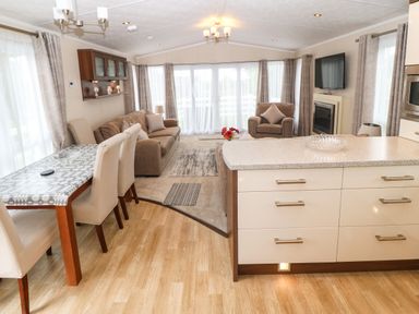A living room and dining area with a sofa armchair dining table and kitchen island at Gwel Eryri in Penmynydd near Llanfairpwllgwyngyll
