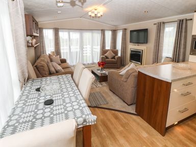 A living room with sofas a dining table and a kitchen counter at Gwel Eryri in Penmynydd near Llanfairpwllgwyngyll