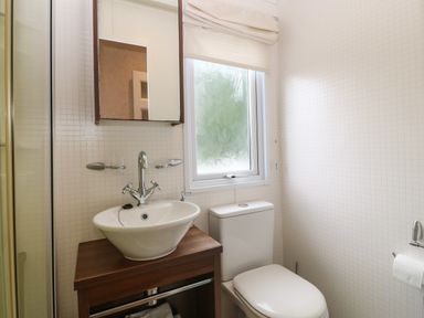 A bathroom with a sink on a wooden cabinet a mirror window and a toilet at Gwel Eryri in Penmynydd near Llanfairpwllgwyngyll